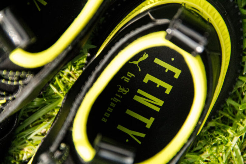 Fenty x Puma sneakers in grass with logo on inside displayed prominently