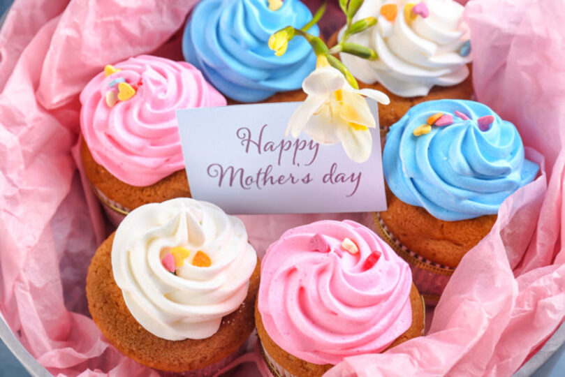 Basket of cupcakes lined with pink paper and a note reading "Happy Mother's Day"