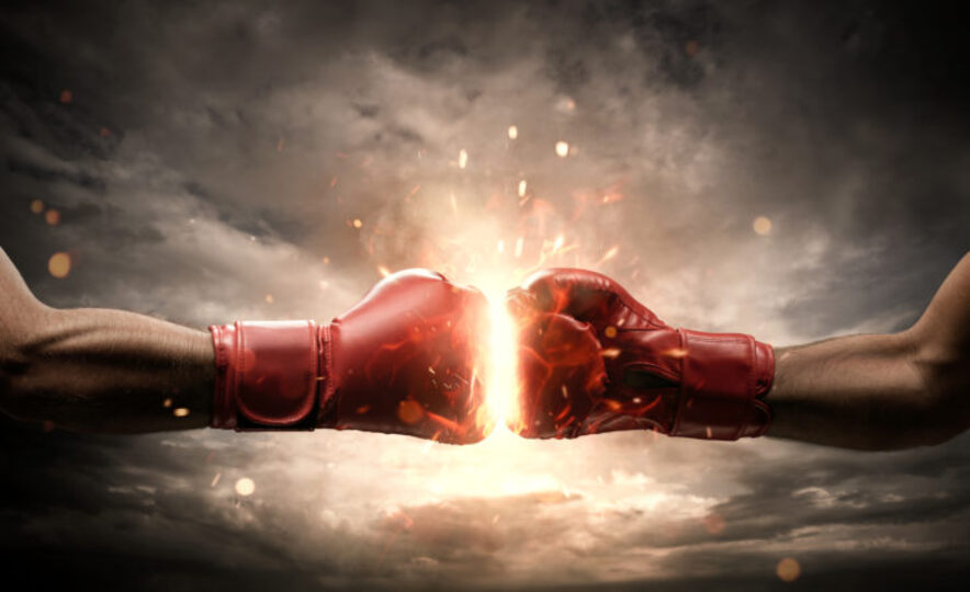 Red boxing gloves are powered together with fire in between them.