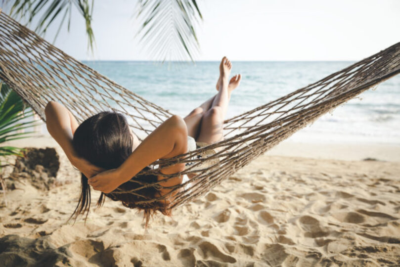Beautiful girl hanging in a hammock on the beach