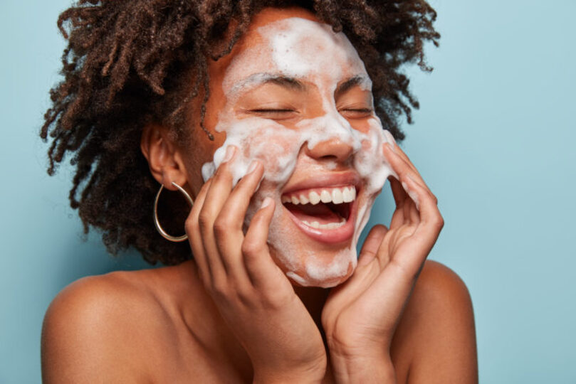 woman with soap all over face cleaning it