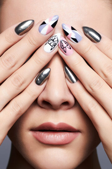 cool nail art on womans finger nails while hands covering her eyes