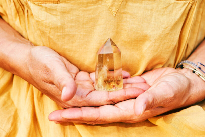 Someone in a yellow shirt holding a citrine crystal