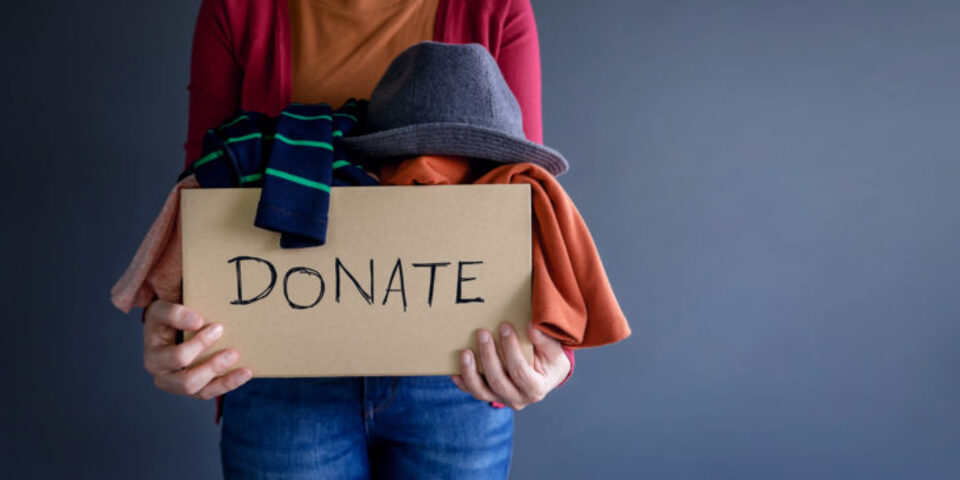 woman holding a donate box full of clothes