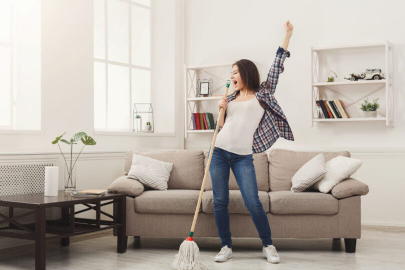Woman sining into a mop in her living room