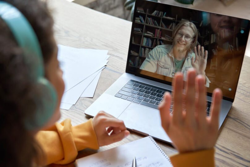 A child attending a virtual meeting with an older male teacher