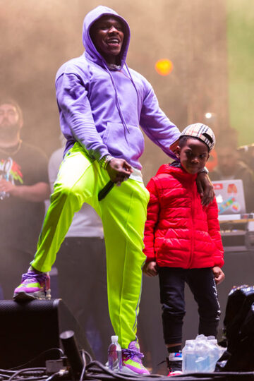 Dababy standing next to a child onstage at an event