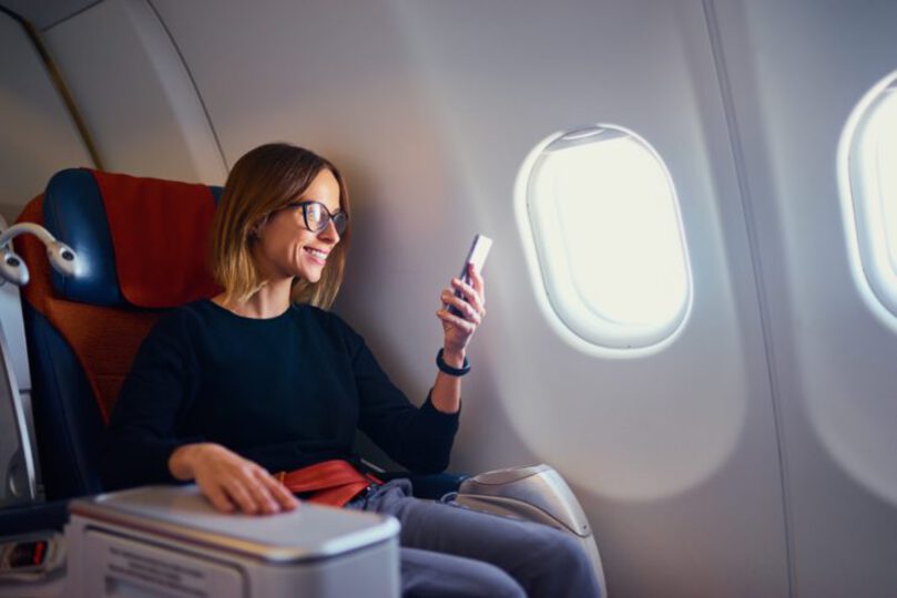 Woman using her phone on a plane during the day