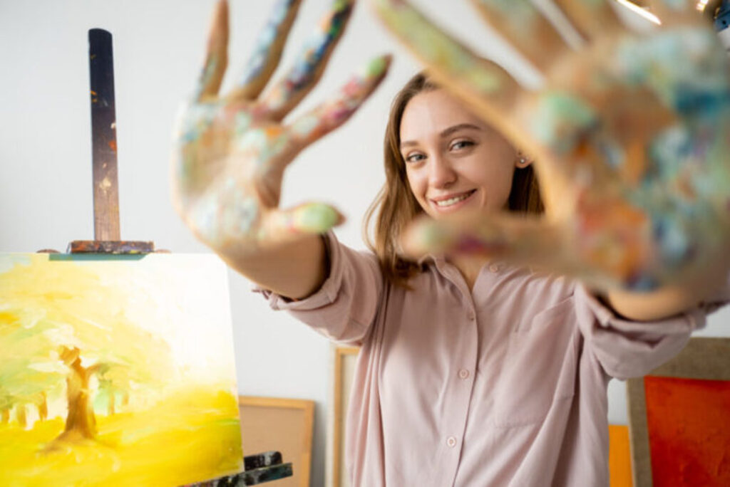 A woman showing off her hands covered in paint 